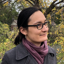 Non-binary person with long hair, glasses, and earrings, mixed East Asian descent