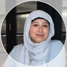 South Asian women in her 20&#039;s, wearing a light blue hijab and light blue dress, smiling. 